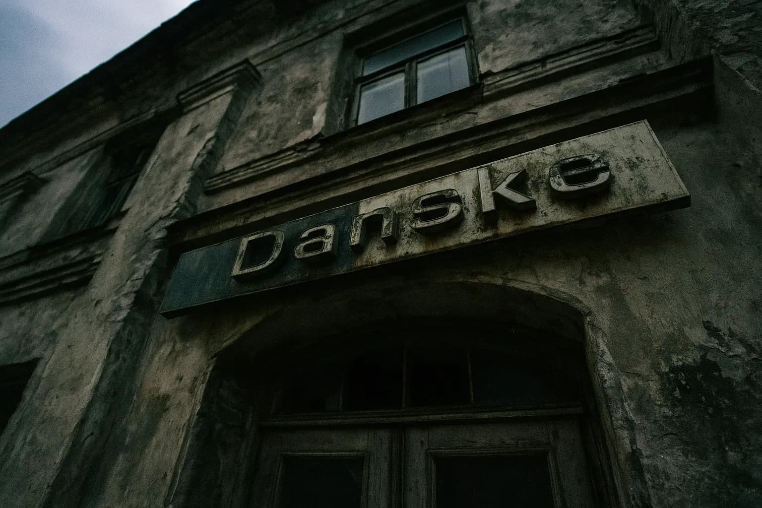 Et slidt Danske Bank-logo sidder over indgangen til en forfalden bygning i Estland, hvilket symboliserer den €200 milliarder store hvidvaskningsskandale og det efterfølgende firmafald.