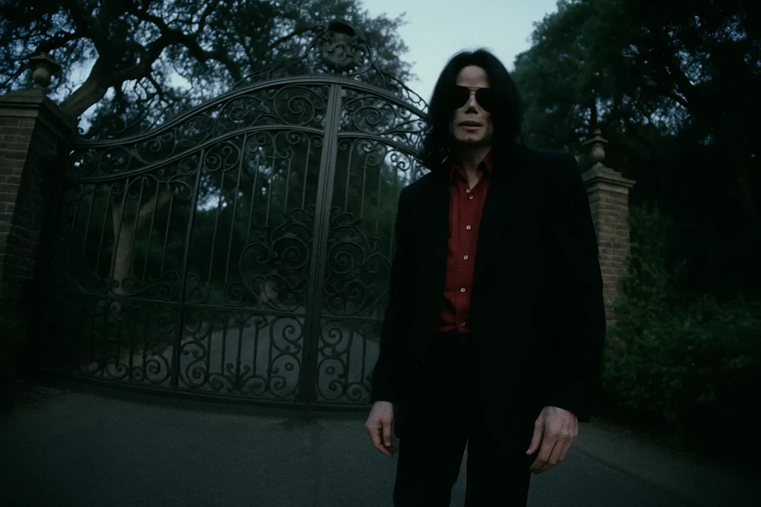 En skikkelse, der ligner Michael Jackson, står ved portene til Neverland Ranch, et sted centralt for retssagen i 2005, omgivet af den udsmykkede smedejern og frodig grønne områder af ejendommen.